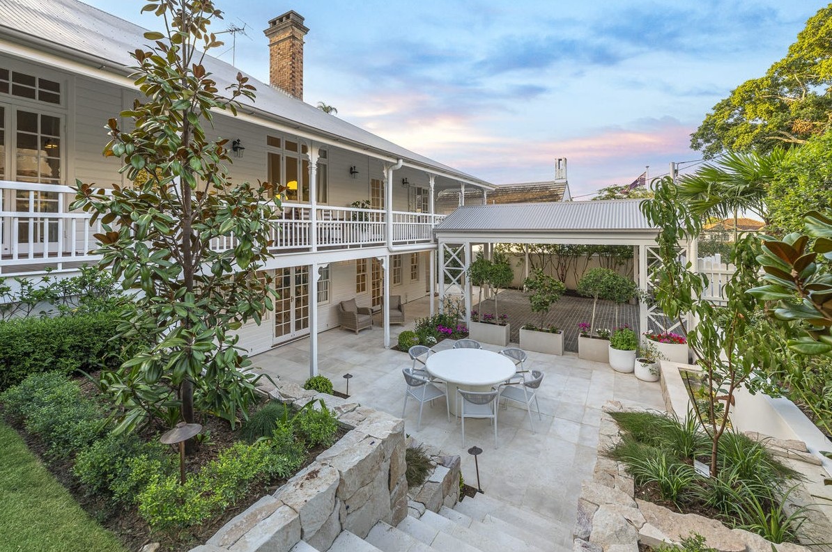 Restored Queenslander with wraparound verandahs and stone courtyard at dusk