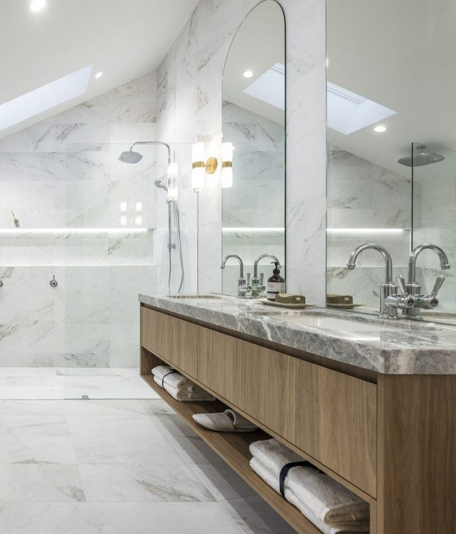 Marble bathroom with double vanity, arched mirror and skylights