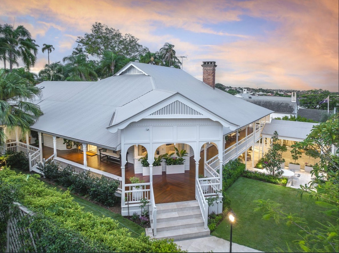 Aerial view of restored Queenslander with gabled verandah and tropical gardens at dusk