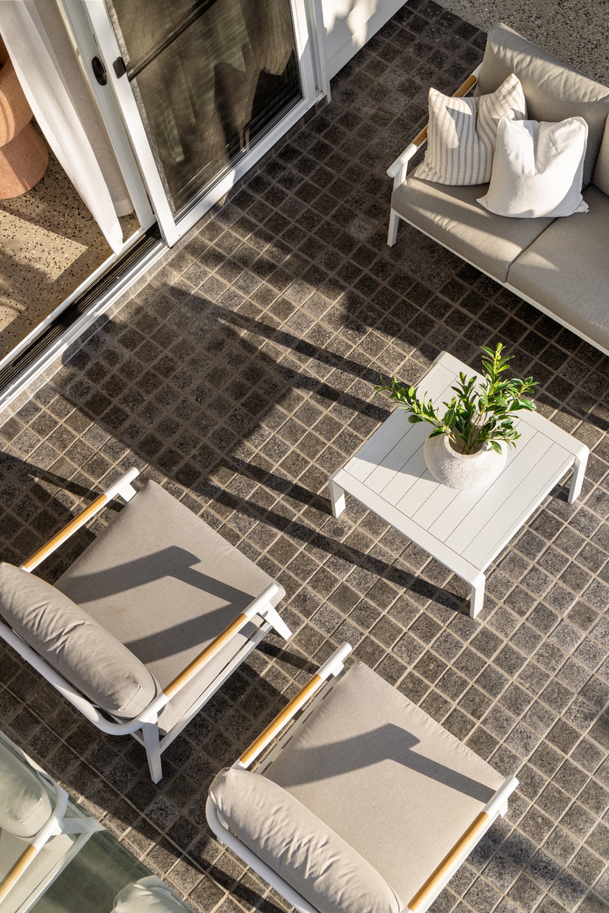 Outdoor terrace with grid stone paving and crisp white lounge furniture, Geebung