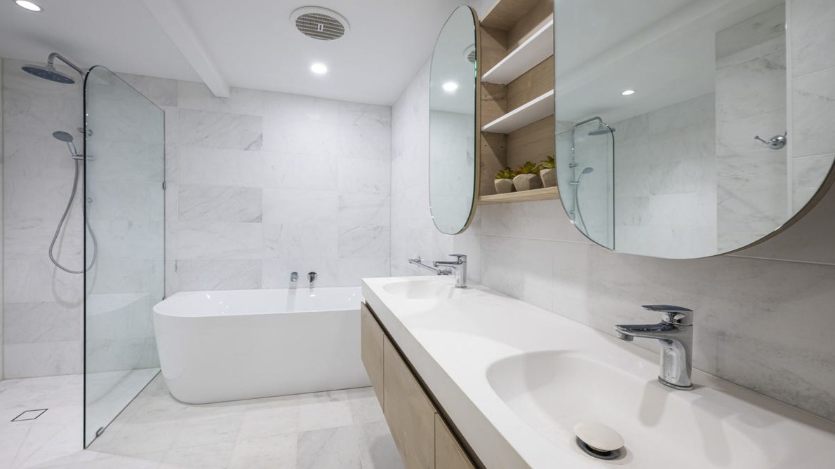 Marble bathroom with freestanding bath, walk-in shower and twin oval mirrors