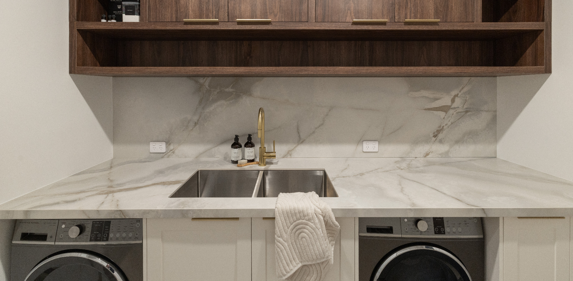 Laundry with marble benchtop, walnut joinery and brass tapware, Geebung